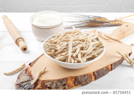 Whole grain wheat raw apulian pasta called Pizzarieddi or maccaruni on a ceramic plate on white wooden table 85738451