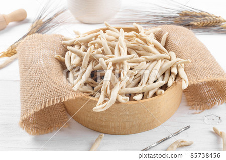 Whole grain wheat raw apulian pasta called Pizzarieddi or maccaruni in a sieve on white wooden table 85738456