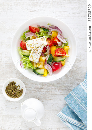 Fresh summer vegetable salad with lettuce, tomato, cucumber, bell pepper, onion and feta cheese, dressed with olive oil. Top view Fresh summer vegetable salad with lettuce, tomato, cucumber, bell pepper, onion and feta cheese, dressed with olive oil. Top view 85738799