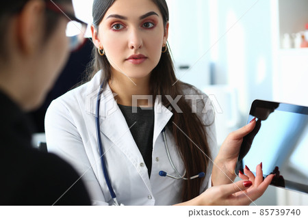 Doctor explains diagnosis to patient holding and showing digital tablet pc Doctor explains diagnosis to patient holding and showing digital tablet pc 85739740