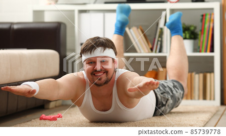 Man lies with excess weight doing exercises lying for spine at home Man lies with excess weight doing exercises lying for spine at home 85739778