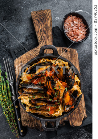 Mafaldine pasta with mussels and tomato sauce. Black background. Top view 85740252