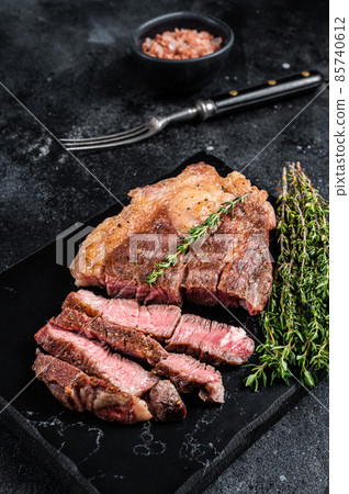 Roasted bbq Chuck Roll beef steaks with herbs. Black background. Top view 85740612