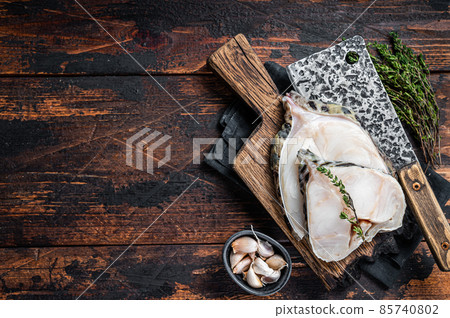 Fresh Raw wolffish o wolf fish Steak on a butcher board. Dark wooden background. Top view. Copy space 85740802
