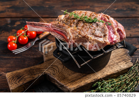 Grilled Tomahawk rib eye steak on grill with herbs. Wooden background. Top view 85740829