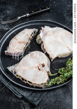 Fresh Raw wolffish o wolf fish Steak on a plate. Black background. Top view Fresh Raw wolffish o wolf fish Steak on a plate. Black background. Top view 85740958