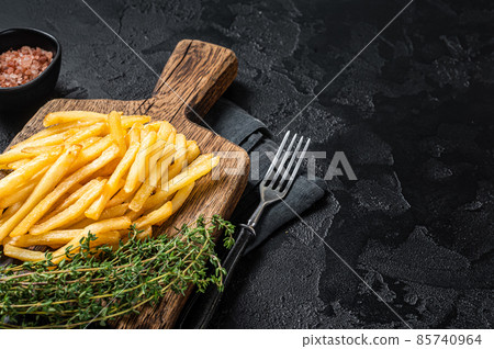 Tasty french fries on wooden cutting board. Black background. Top view. Copy space 85740964