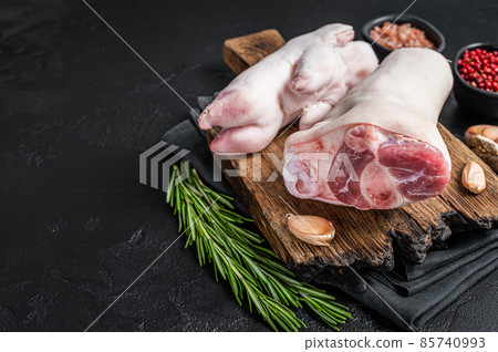 Raw pork knuckle or hoof, feet on a cutting board. Black background. Top view. Copy space Raw pork knuckle or hoof, feet on a cutting board. Black background. Top view. Copy space 85740993