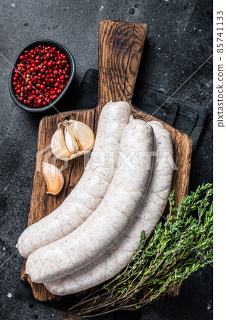 Raw Munich white sausage weisswurst on wooden board. Black background. Top view 85741133