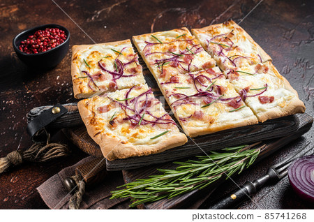 French tarte flambee with cream cheese, bacon and onions. Flammkuchen from Alsace region. Dark background. Top view 85741268