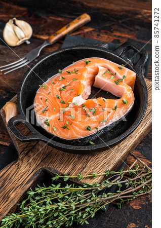 Trout or Salmon raw steaks in a pan with thyme. Dark wooden background. Top view Trout or Salmon raw steaks in a pan with thyme. Dark wooden background. Top view 85741272