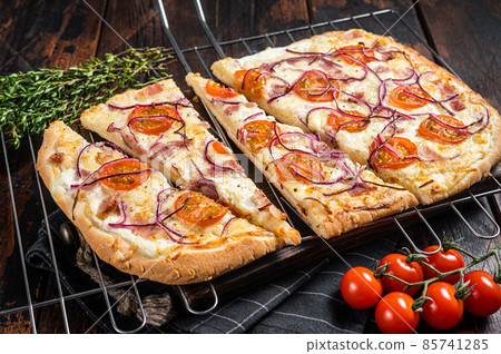 Traditional German pie Flammkuchen or tarte flambee with cream cheese, bacon, tomato and onions. Wooden background. Top view 85741285