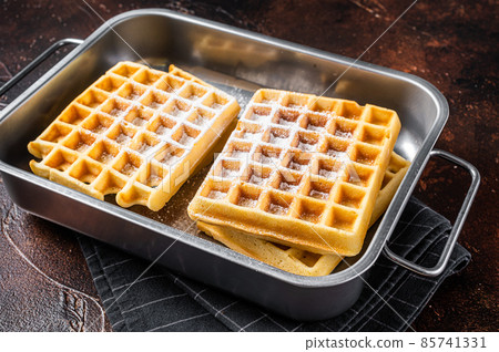 Viennese waffles with powdered sugar in kitchen steel tray. Dark background. Top view Viennese waffles with powdered sugar in kitchen steel tray. Dark background. Top view 85741331