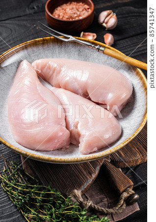 Chicken breast fillet raw meat in plate with herbs. Black Wooden background. Top view Chicken breast fillet raw meat in plate with herbs. Black Wooden background. Top view 85741347
