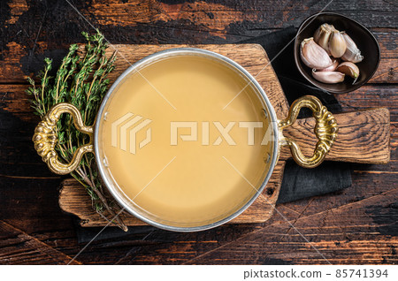 Clear broth stock without meat in cooking skillet. Wooden background. Top view 85741394