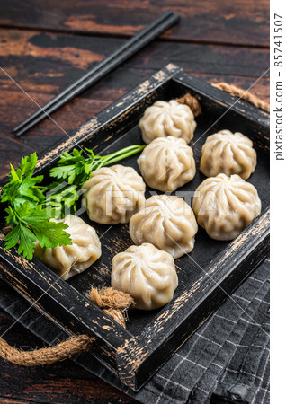 Momo dumplings in a wooden tray with herbs. Dark Wooden background. Top view 85741507