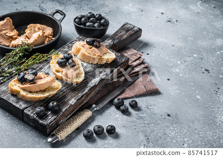 Toast with Foie gras pate and fresh blueberry on wooden board. Gray background. Top view. Copy space 85741517