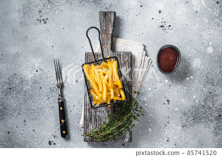 Basket of Fried French fries potatoes with salt on wooden board. Gray background. Top view 85741520