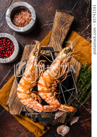 BBQ roasted Giant shrimps Langoustine on grill with herbs. Dark background. Top view BBQ roasted Giant shrimps Langoustine on grill with herbs. Dark background. Top view 85741591