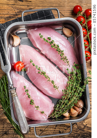 Cooking of Raw Turkey steaks, Breasts fillet with thyme and rosemary. Wooden background. Top view Cooking of Raw Turkey steaks, Breasts fillet with thyme and rosemary. Wooden background. Top view 85741596