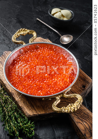 Red caviar in skillet on wooden board. Balck background. Top view 85741623