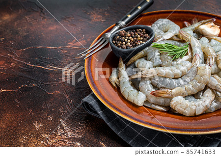 Black Raw uncooked Headless giant shrimps prawns in a rustic plate. Dark background. Top view. Copy space 85741633