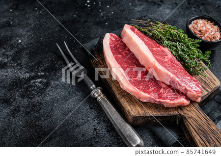 Uncooked Raw rump steak or top sirloin cap beef meat steaks on wooden board. Black background. Top view. Copy space 85741649