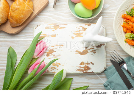 White empty wooden cutting board and Easter food on kitchen table 85741845