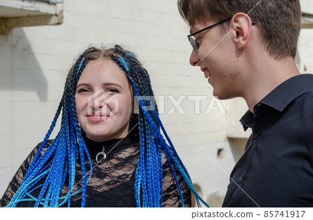 A young adult male is flirting with a female outside. 85741917