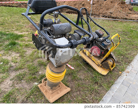 worker compresses sand in blind area around building with special working tool tamping machine 85742309