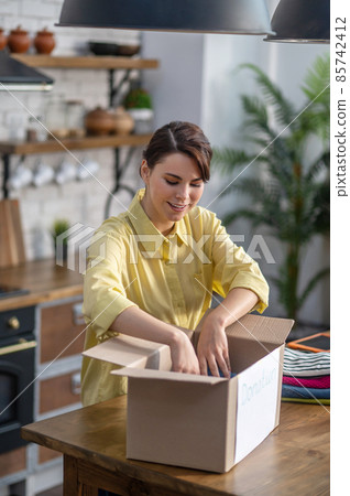 Concentrated young female packing clothes within the carton 85742412