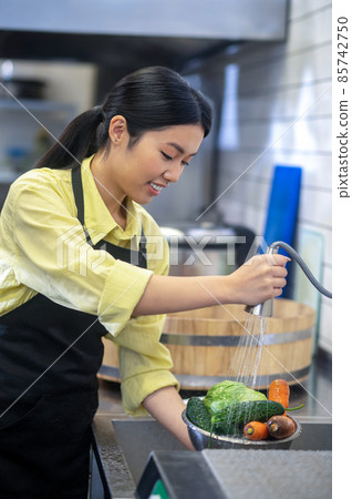 Woman in the kitchen washing vegetables before cooking Woman in the kitchen washing vegetables before cooking 85742750