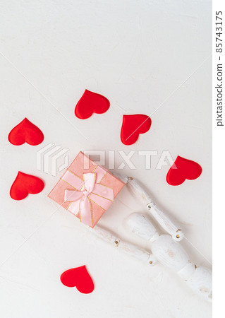 Pink gift box on a white background with a wooden mannequin with red hearts. Top view. Vertical photo Pink gift box on a white background with a wooden mannequin with red hearts. Top view. Vertical photo 85743175