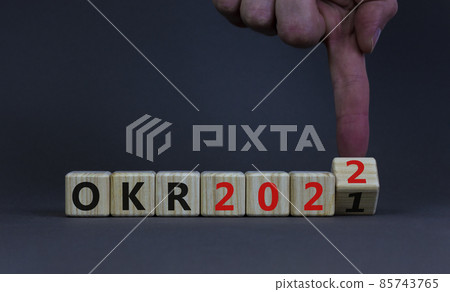 OKR, objectives and key results symbol. Businessman turns a cube with words OKR 2021 and OKR 2022 on beautiful grey background. Business, OKR 2022, objectives and key results concept. Copy space. 85743765