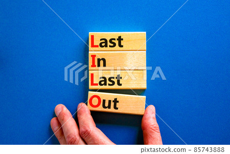 LILO last in last out symbol. Concept words LILO last in last out on wooden blocks. Beautiful blue table blue background. Businessman hand. Business and LILO last in and out concept. Copy space. 85743888