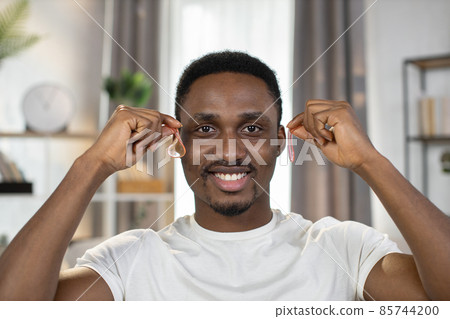 Smiling guy holds in hands pink transparent patches near his eyes Smiling guy holds in hands pink transparent patches near his eyes 85744200