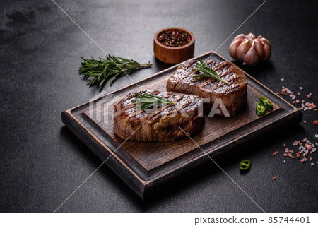 Fresh juicy delicious beef steak on a dark background Fresh juicy delicious beef steak on a dark background 85744401