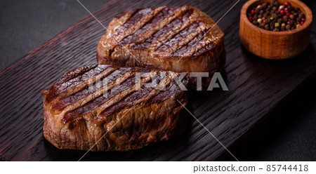 Fresh juicy delicious beef steak on a dark background 85744418