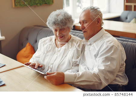 Elegant old couple in a cafe using a tablet Elegant old couple in a cafe using a tablet 85748144