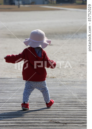 Back view of a 1-year-old child playing on a sandy beach Back view of a 1-year-old child playing on a sandy beach 85752029