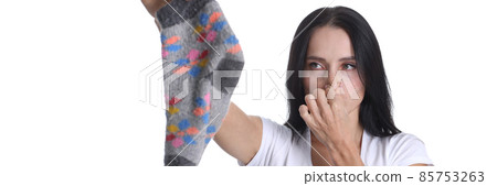 Portrait of young woman covering nose and holding sock in hand closeup Portrait of young woman covering nose and holding sock in hand closeup 85753263