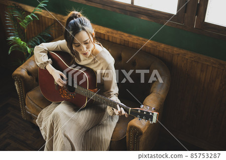 A woman playing the guitar 85753287