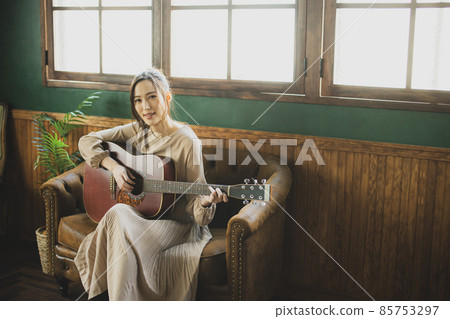 A woman playing the guitar 85753297