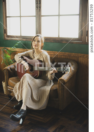 A woman playing the guitar A woman playing the guitar 85753299