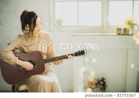 A woman playing the guitar A woman playing the guitar 85753307
