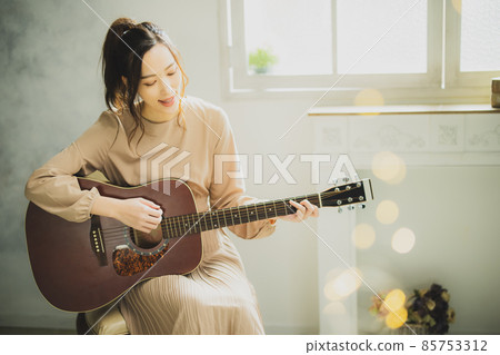 A woman playing the guitar 85753312