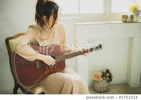 A woman playing the guitar 85753318