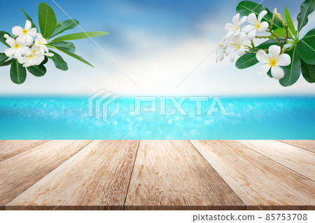 Wooden table top with blurry sea sun sky scenery decorate with plumeria flower branch tropical summer background Wooden table top with blurry sea sun sky scenery decorate with plumeria flower branch tropical summer background 85753708