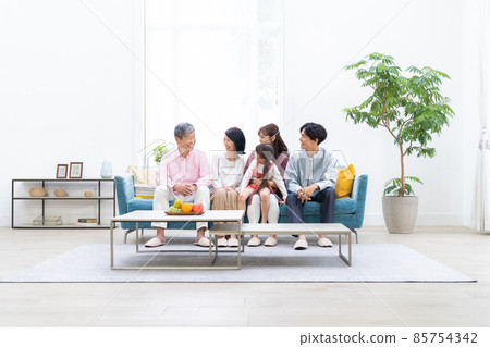Three-generation family relaxing in the living room 85754342