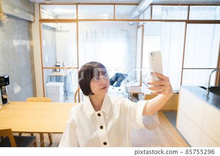 一個女人在室內拿著智能手機 一個女人在室內拿著智能手機 85755296